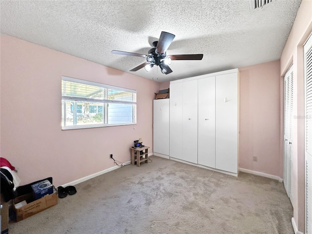 unfurnished bedroom featuring ceiling fan, light carpet, and a textured ceiling