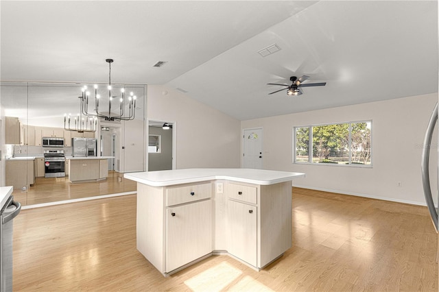 kitchen with pendant lighting, a center island, lofted ceiling, ceiling fan with notable chandelier, and stainless steel appliances