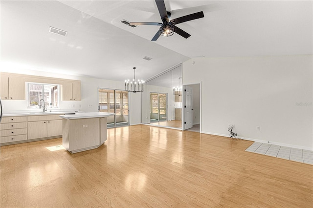 kitchen featuring ceiling fan with notable chandelier, sink, light brown cabinets, a center island, and lofted ceiling