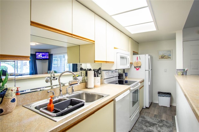 kitchen with dark hardwood / wood-style flooring, sink, white cabinets, and white appliances