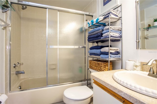 full bathroom with vanity, bath / shower combo with glass door, and toilet