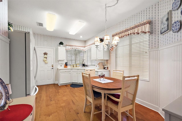 dining area with light hardwood / wood-style flooring and a chandelier