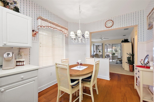 dining space featuring ceiling fan with notable chandelier and wood-type flooring