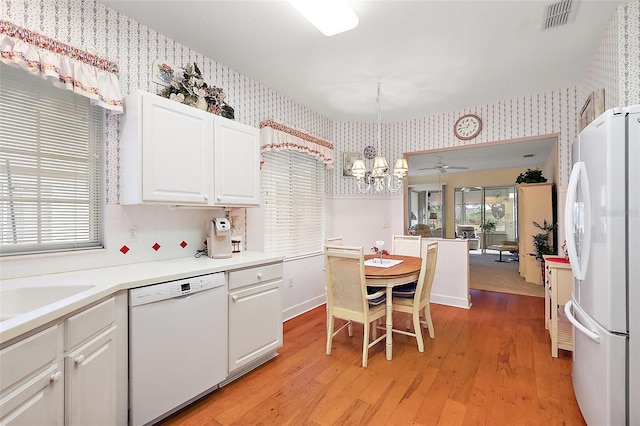 kitchen featuring white appliances, pendant lighting, white cabinets, light hardwood / wood-style flooring, and ceiling fan with notable chandelier