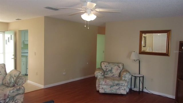 living area featuring ceiling fan, washer / dryer, and dark wood-type flooring