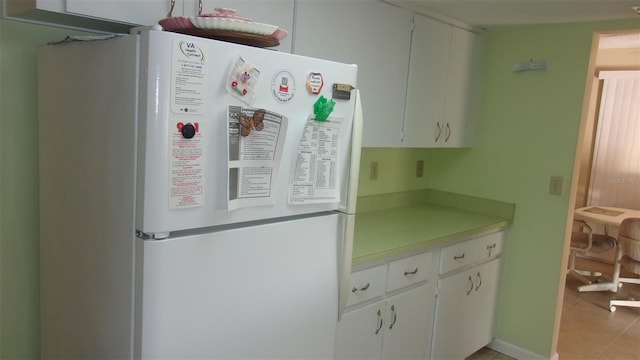 kitchen featuring white cabinets, light tile patterned flooring, and white refrigerator