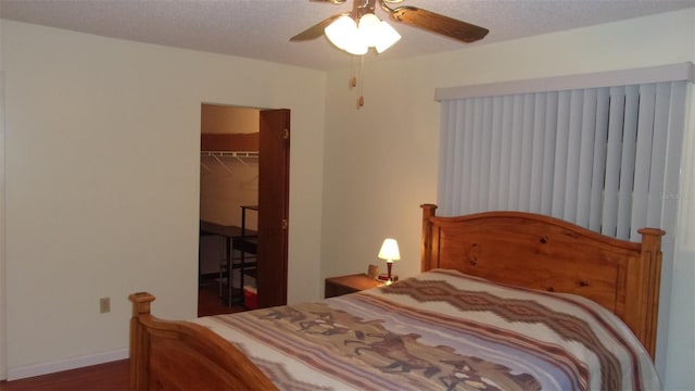 bedroom featuring a walk in closet, ceiling fan, a closet, and a textured ceiling