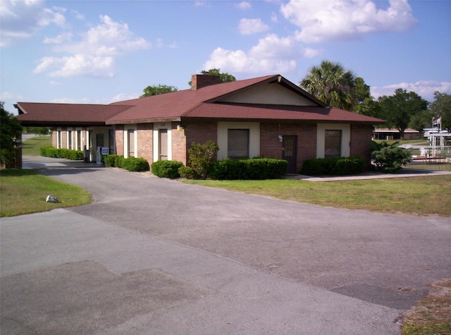 ranch-style house featuring a front lawn and a carport