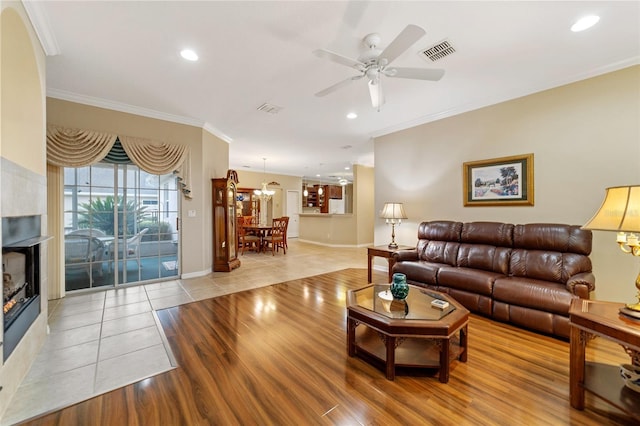 tiled living room with ornamental molding, a tiled fireplace, and ceiling fan