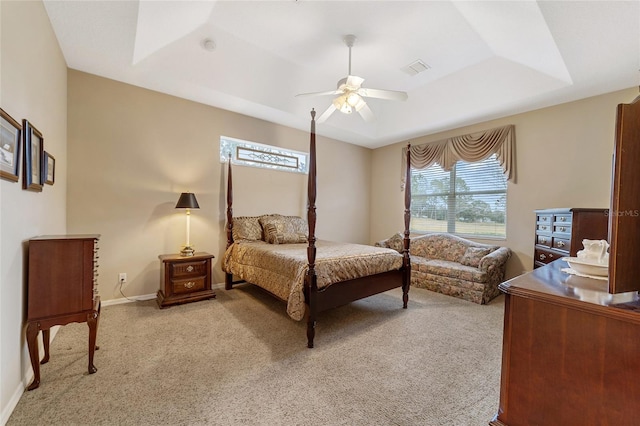 bedroom featuring ceiling fan, light colored carpet, and a tray ceiling