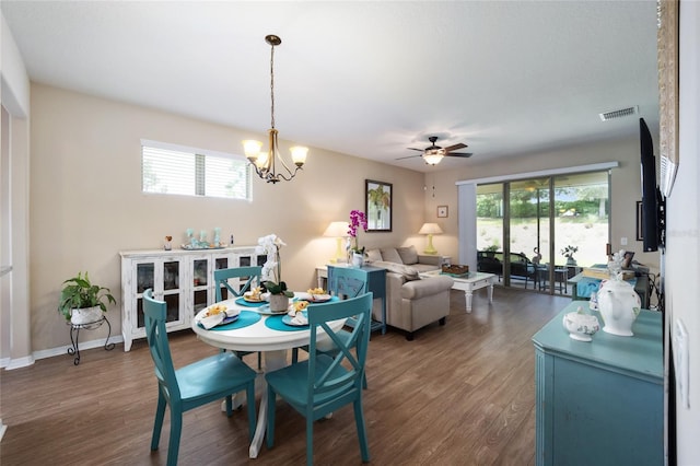 dining area featuring ceiling fan with notable chandelier and dark wood-type flooring