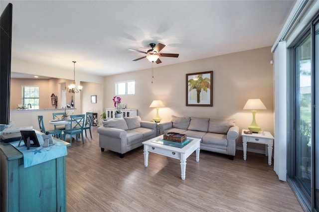 living room with plenty of natural light, wood-type flooring, and ceiling fan with notable chandelier