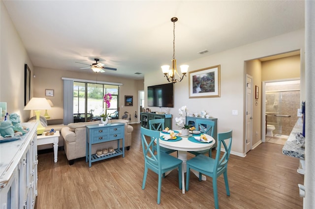 dining room with ceiling fan with notable chandelier and light wood-type flooring