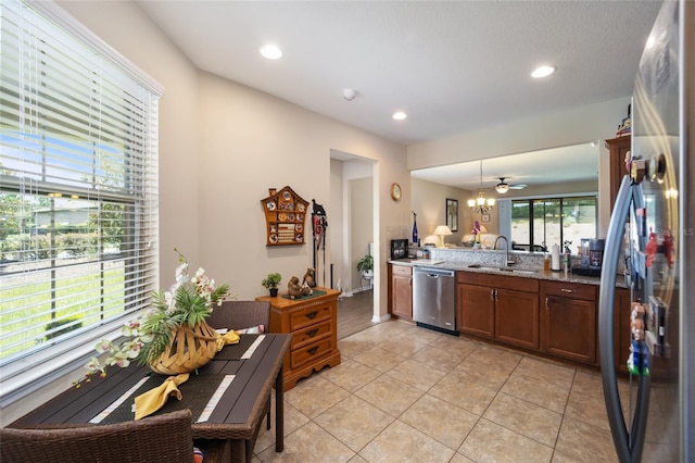 kitchen featuring light stone countertops, appliances with stainless steel finishes, sink, light tile patterned floors, and hanging light fixtures