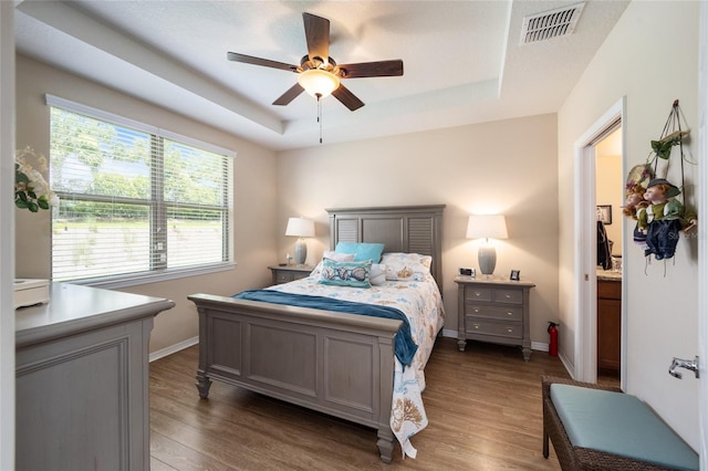 bedroom with a tray ceiling, ceiling fan, and dark hardwood / wood-style flooring