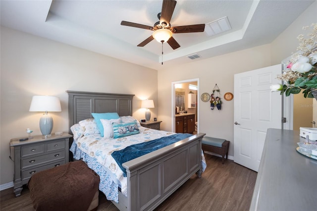 bedroom featuring ceiling fan, dark hardwood / wood-style flooring, ensuite bathroom, and a tray ceiling