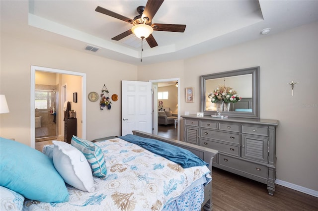 bedroom featuring ensuite bathroom, ceiling fan, a raised ceiling, and dark wood-type flooring