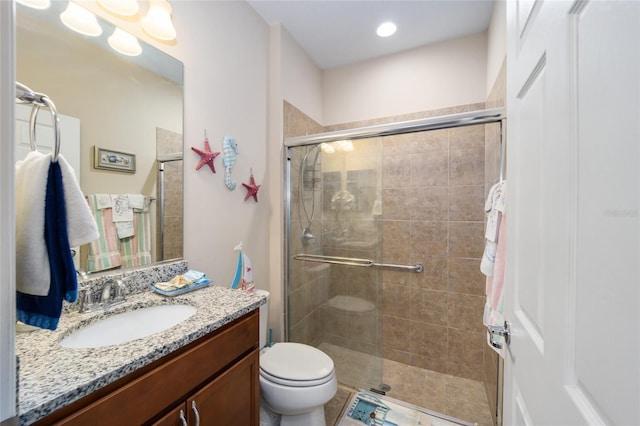 bathroom with vanity, a shower with shower door, and toilet