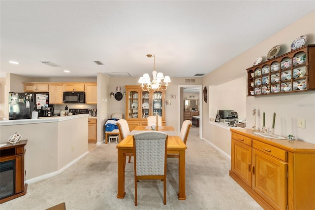 dining room with light colored carpet and a notable chandelier