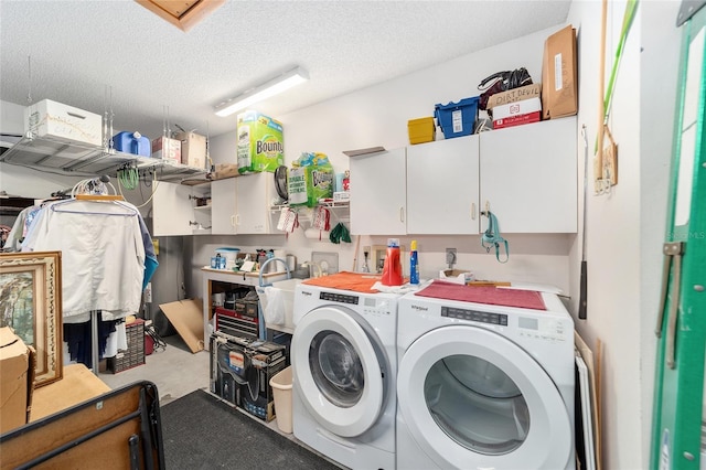 laundry area with washing machine and clothes dryer, cabinets, and a textured ceiling