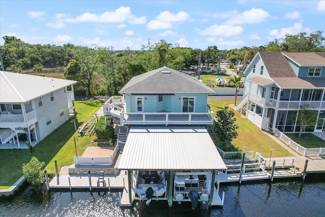 rear view of property featuring a lawn, a water view, and boat lift