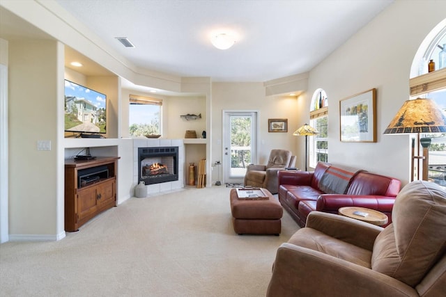 living room with a tile fireplace, light colored carpet, and built in shelves