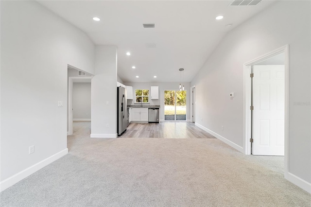 unfurnished living room featuring light carpet and vaulted ceiling