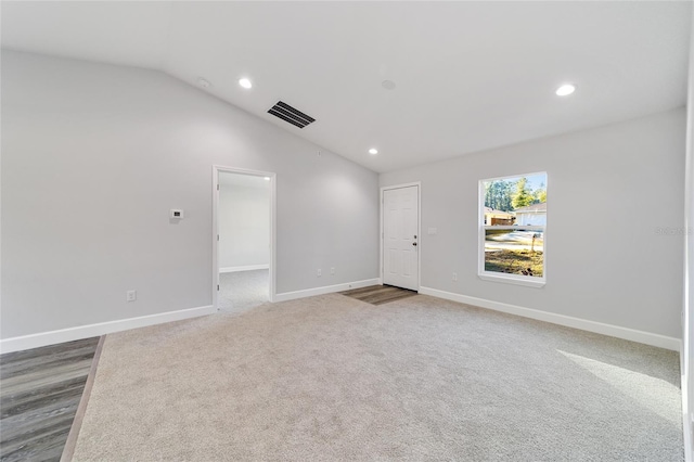 spare room with carpet flooring and lofted ceiling