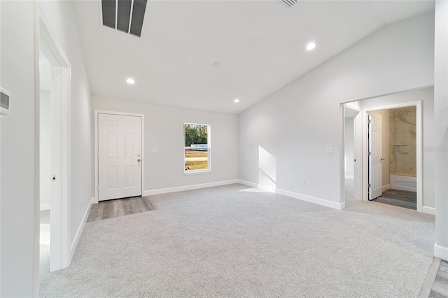 unfurnished room featuring light colored carpet and vaulted ceiling