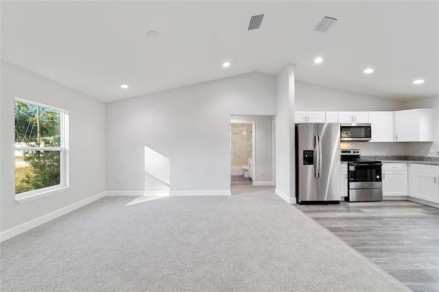 kitchen featuring lofted ceiling, white cabinetry, light carpet, and appliances with stainless steel finishes