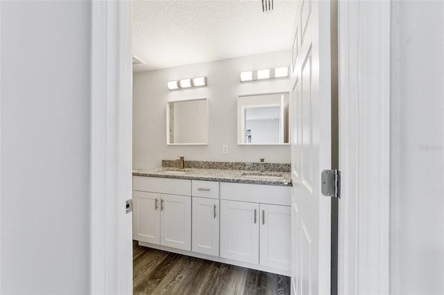 bathroom featuring vanity, wood-type flooring, and a textured ceiling