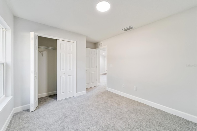 unfurnished bedroom with a closet and light colored carpet