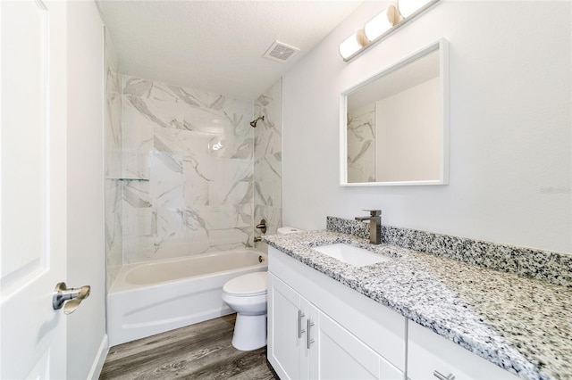 full bathroom featuring vanity, tiled shower / bath combo, toilet, a textured ceiling, and wood-type flooring