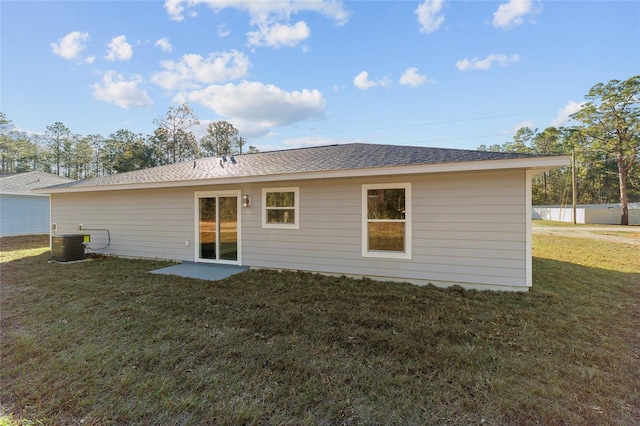 back of property with central AC and a lawn