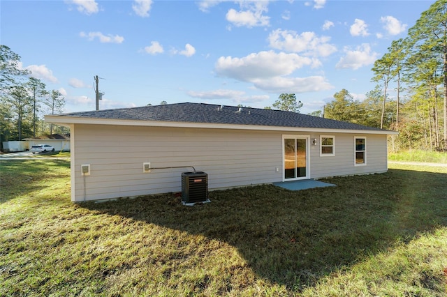 rear view of property with central air condition unit and a lawn