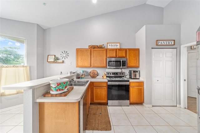 kitchen featuring kitchen peninsula, sink, light tile patterned flooring, and appliances with stainless steel finishes