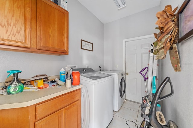 washroom with washing machine and dryer, light tile patterned floors, and cabinets