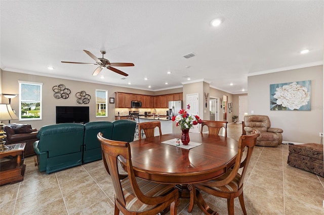 dining area with ceiling fan, sink, and crown molding