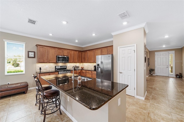 kitchen featuring sink, stainless steel appliances, crown molding, a breakfast bar area, and a kitchen island with sink