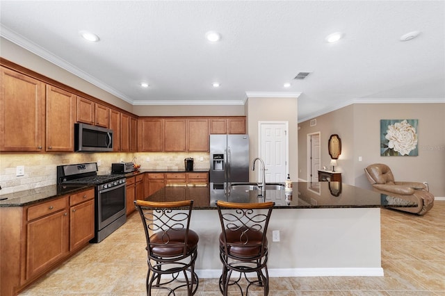 kitchen with crown molding, stainless steel appliances, a breakfast bar area, and an island with sink