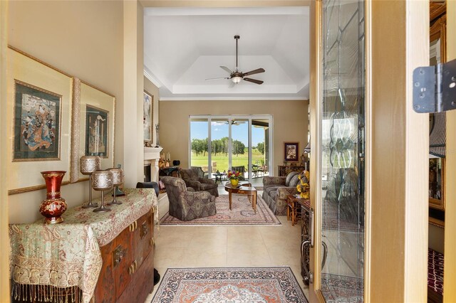 living room featuring ceiling fan, light tile patterned floors, and a tray ceiling