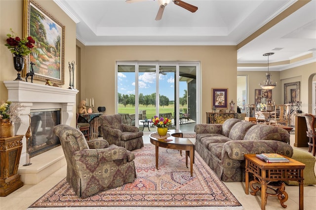 living room with a raised ceiling, ceiling fan, and ornamental molding