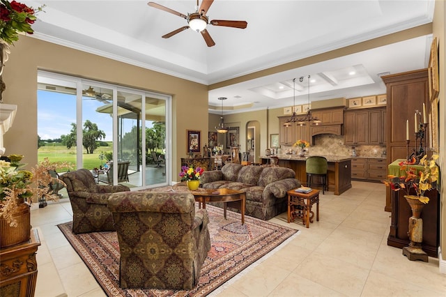 living room with a raised ceiling, ceiling fan, and ornamental molding