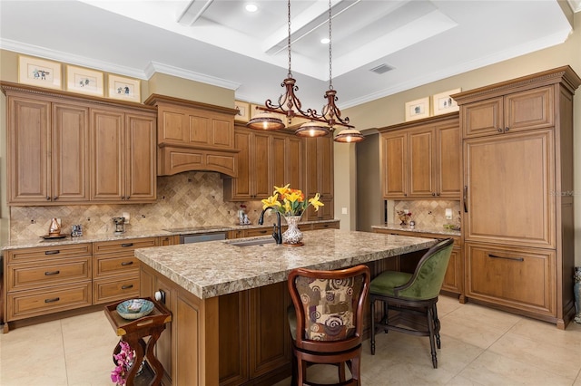 kitchen with tasteful backsplash, a raised ceiling, sink, pendant lighting, and an island with sink