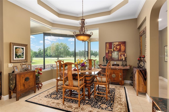 tiled dining space featuring a raised ceiling and ornamental molding