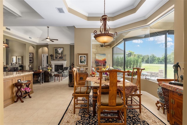 dining space with a raised ceiling, crown molding, ceiling fan, and light tile patterned flooring