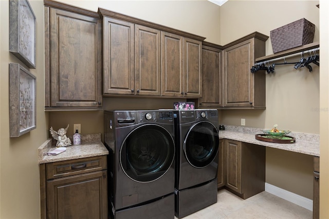 laundry area with washer and clothes dryer, cabinets, and light tile patterned floors