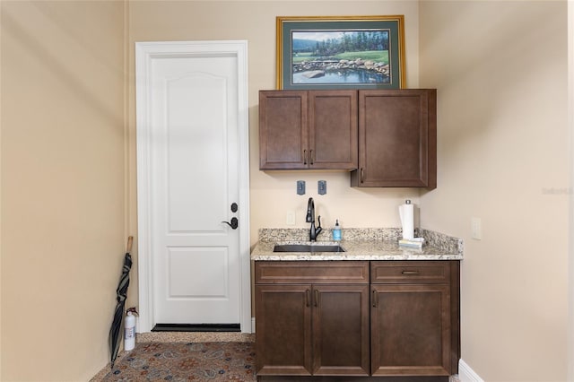 interior space featuring light stone counters, sink, and dark brown cabinets