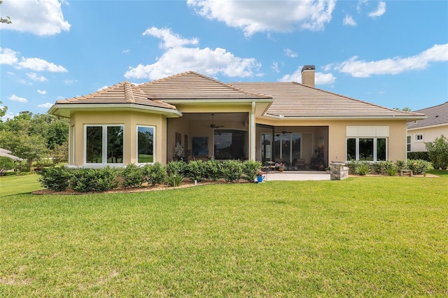 rear view of property with ceiling fan and a yard