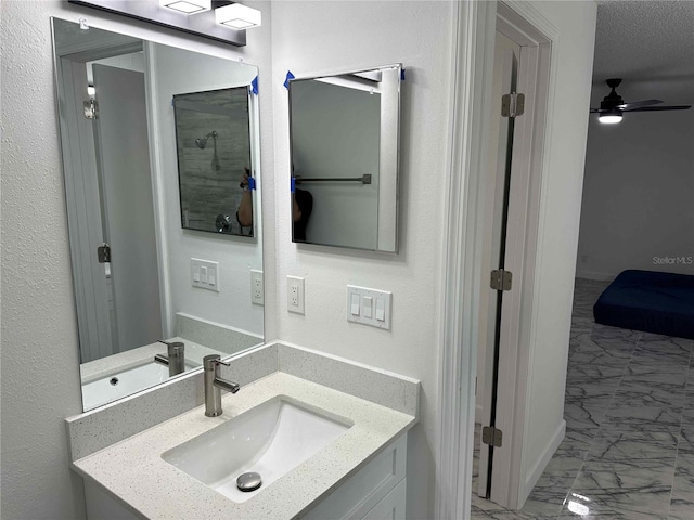 bathroom with vanity, ceiling fan, and a textured ceiling